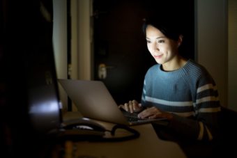 暗い部屋でパソコンを使っている女性