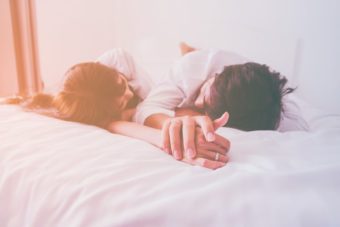 ベッドで寝そべり手を繋ぐカップル