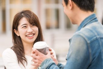 笑顔で男性からコーヒーを受け取る女性